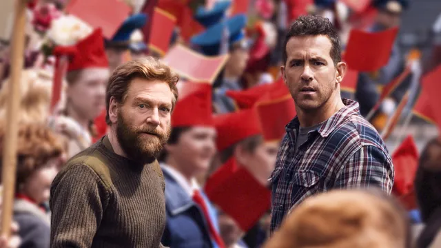 Ryan Reynolds et Kenneth Branagh dans le film Mayday, au milieu d'une foule soviétique brandissant des drapeaux rouges