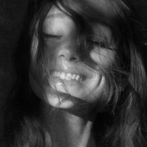 Pochette de l'album Petal d'Ariana Grande : portrait en noir et blanc de la chanteuse souriante, les cheveux devant le visage