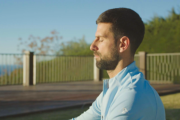Novak Djokovic yeux fermes en train de mediter au soleil, image officielle du documentaire Prime Video Le Loup en hiver