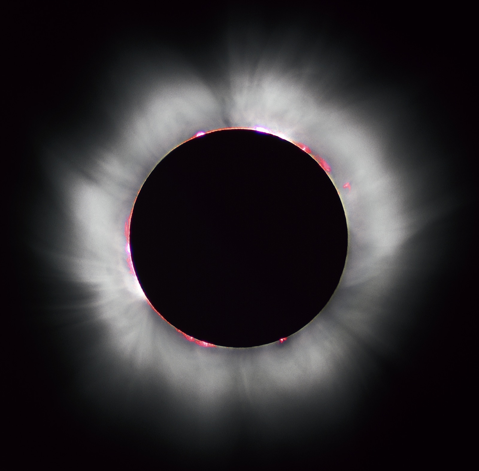 Éclipse solaire totale : la couronne du Soleil et des protubérances roses autour du disque noir de la Lune