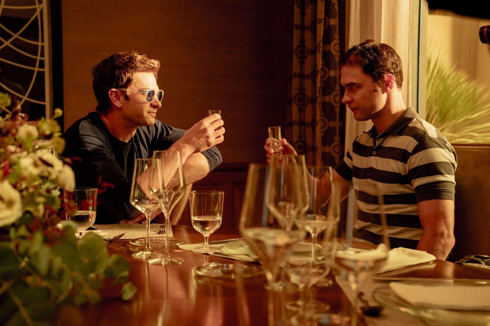 Andrew Garfield (Sam Altman) et Yura Borisov (Ilya Sutskever) trinquent dans une scene du film Artificial de Luca Guadagnino