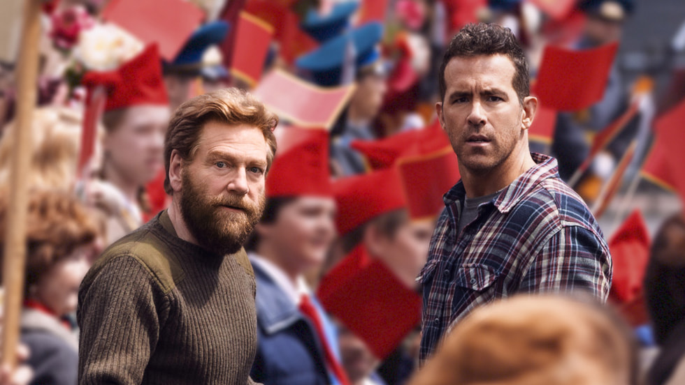 Ryan Reynolds et Kenneth Branagh dans le film Mayday, au milieu d'une foule soviétique brandissant des drapeaux rouges