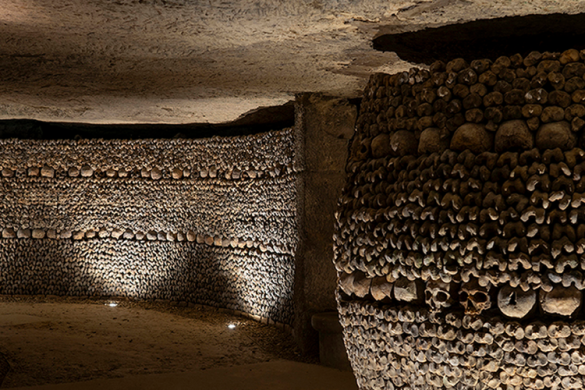 Galerie d'ossements des Catacombes de Paris, avec un pilier de crânes et une croix, lieu de l'exposition Nadar