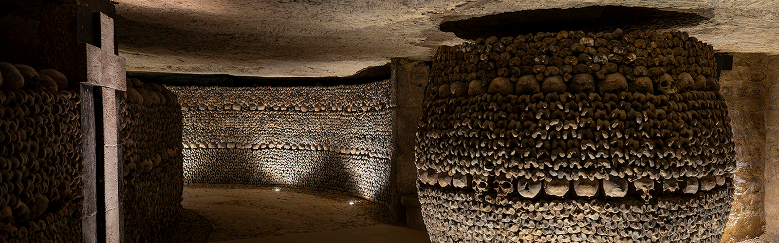 Galerie d'ossements des Catacombes de Paris, avec un pilier de crânes et une croix, lieu de l'exposition Nadar