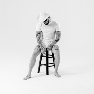 Pochette de l'album Mule d'Orville Peck : un homme tatoué assis sur un tabouret, tête baissée, coiffé d'un chapeau de cowboy blanc