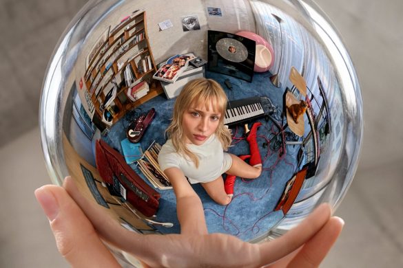 Pochette de l'album Instinct d'Angèle : la chanteuse dans une boule de cristal entourée de ses objets, hommage à Escher