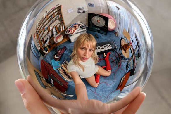 Pochette de l'album Instinct d'Angèle : la chanteuse dans une boule de cristal tenue à bout de bras, clin d'oeil à Escher